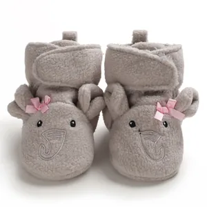 Dettaglio di scarpine per neonati a forma di elefante grigio con fiocchi rosa e pile