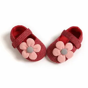 Detail view of red knitted baby girl princess shoes with large pink flower decoration