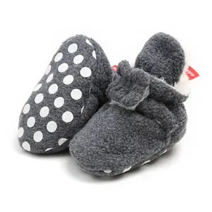 Detail of warm grey plush baby booties with soft soles and white polka dot pattern