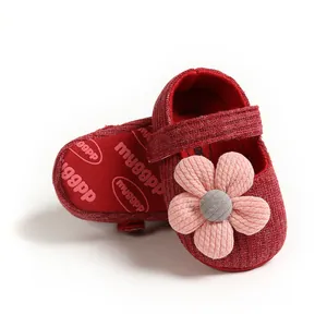 Close-up of red knitted baby princess shoes with a soft pink decorative flower.