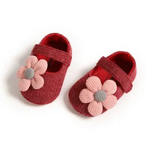 Close-up of red infant princess shoes with pink knit flower and soft sole.