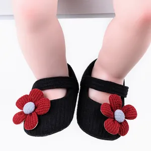 Close-up view of black knitted baby walking shoes with red flower decoration for infant girls