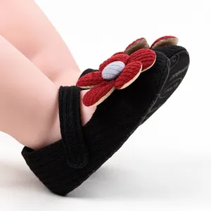Detail view of infant girls' black knitted pre-walker shoes featuring a large red flower