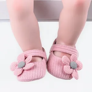Close-up of pink knitted baby girl walking shoes with decorative flower detail