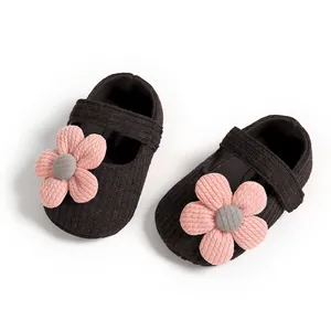 Top-down detail of black baby princess shoes with pink knit flower accents