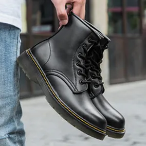 Détail de bottines de travail en cuir noir avec surpiqûres jaunes et semelle translucide.