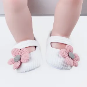 Detailed macro view of white knitted baby shoes featuring decorative pink flowers