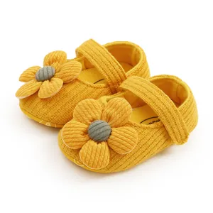 Detailed close-up of yellow knit baby shoes featuring a decorative flower and soft sole
