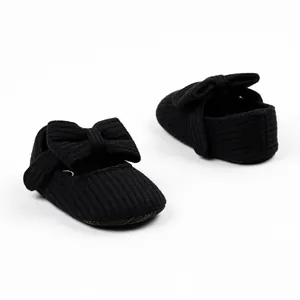 Detail view of black ribbed infant pre-walker shoes featuring an elegant bow design
