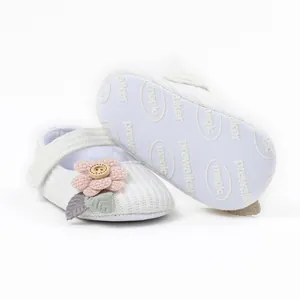 Close-up of cute white baby girl princess walking shoes with flower detail