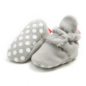 Close-up detail of grey winter fleece baby booties featuring non-slip white polka dot soles