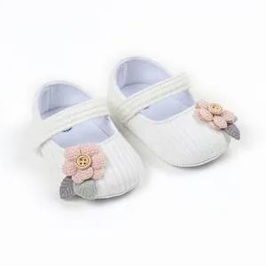 Detailed view of white baby girl walking shoes with pink fabric flower and wood button décor