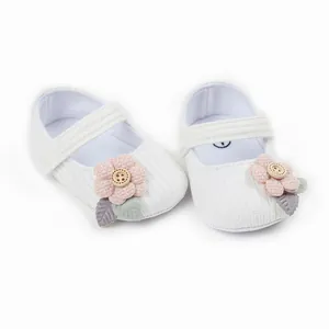 Close-up of white baby girl princess shoes with pink fabric flowers and wooden buttons