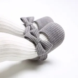 Vista detallada de zapatos de bebé tejidos en gris con suela blanda y un elegante lazo