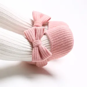 Primer plano de zapatos de bebé de punto rosa con lazo y leotardos blancos acanalados
