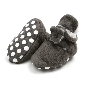 Detail view of soft dark grey fleece baby booties with non-slip polka dot sole.