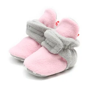 Close-up view of cozy pink and grey fleece baby booties featuring soft anti-slip soles