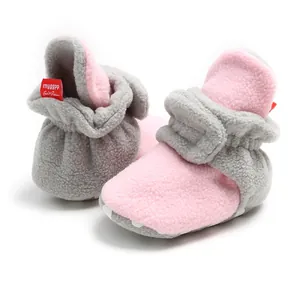 Close-up detail of warm grey and pink fleece baby booties with soft soles for winter