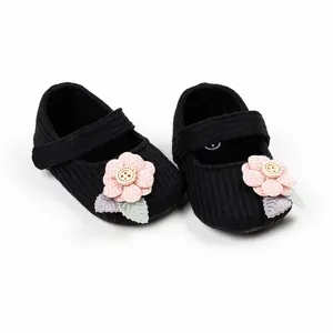 Detailed view of cute black knitted baby girl princess shoes with pink floral decor.