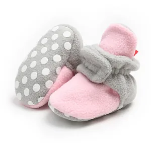 Close-up of soft pink fleece baby boots showing the anti-slip polka dot soles.