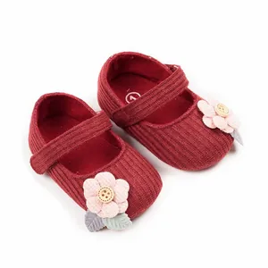 Close-up detail of red corduroy baby girl princess walking shoes with pink flower decoration