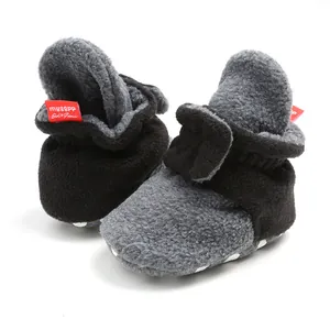 Close-up view of warm fleece infant booties with soft anti-slip soles and red label.