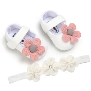 Detailed view of white knit baby princess shoes with pink floral and matching headband