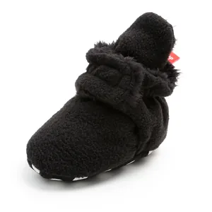 Soft black fleece baby bootie with warm lining and decorative red tag detail.