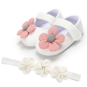 Detail of white knit baby girl princess shoes with pink flowers and matching headband