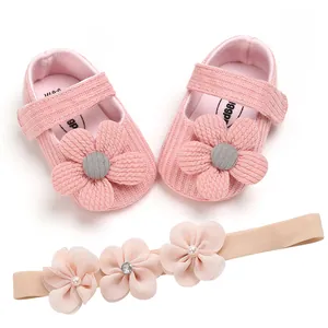 Close-up of pink knitted baby princess shoes with matching flower headband set