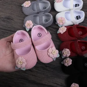 Close-up of pink baby girl princess walking shoes with floral detail on wood background