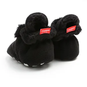 Detailed view of black fleece baby booties featuring red brand tag and plush texture