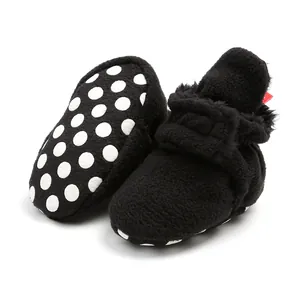 Detailed view of warm black fleece infant booties with white polka dot soft anti-slip soles