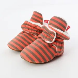 Detailed view of soft-soled orange striped baby booties with warm white fleece lining