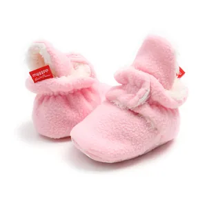 Detailed view of pink fleece baby booties with white faux fur lining and soft warm soles