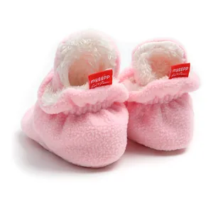 Detailed macro view of soft pink plush baby booties featuring warm white fleece lining