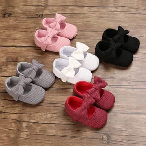 Soft sole knitted baby walking shoes with bow detail in various colors on wood