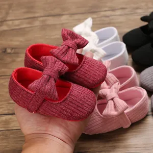Detailed view of red soft-sole knitted baby walking shoes with delicate bow decoration.
