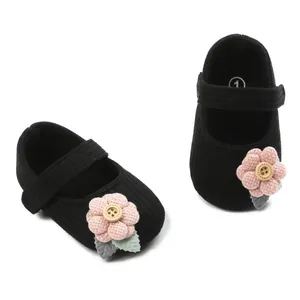 Detailed view of black knit baby Mary Jane shoes with pink flower and wooden button.