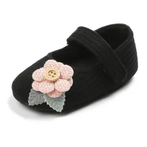 Detail of baby knit walking shoes with decorative pink flower and wooden button