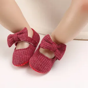 Detailed view of red knitted baby walking shoes featuring a large soft decorative bow