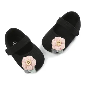 Close-up of knit baby girl shoes with pink flower and wooden button details