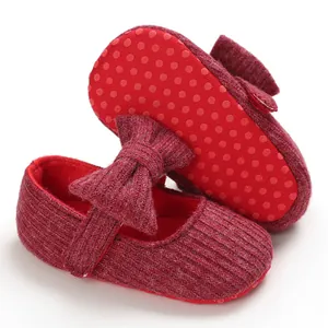 Detailed view of red knitted baby shoes with bow and non-slip dotted sole