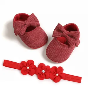 Vista detallada de zapatos de bebé rojos de punto con lazos y diadema floral a juego