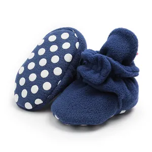 Soft navy fleece baby booties detail featuring non-slip white polka dot soles.