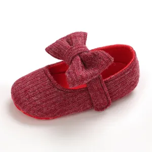 Close-up view of red knitted baby princess shoe with a soft sole and a large bow