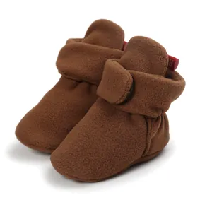 Detailed close-up of brown fleece baby booties featuring soft soles and secure velcro closure