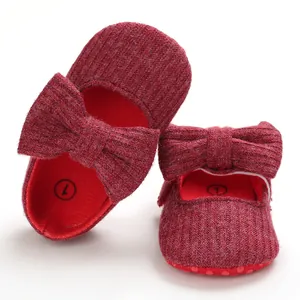 Close-up detail of soft red knitted baby walking shoes with cute bow design for infants