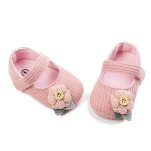 Macro detail of pink knitted baby princess shoes featuring a decorative flower with wooden button