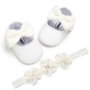 Vista detallada de zapatos de princesa para bebé de punto blanco con lazo y diadema